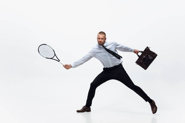 Time for movement. Man in office clothes plays tennis isolated on white studio background. - 写真・画像