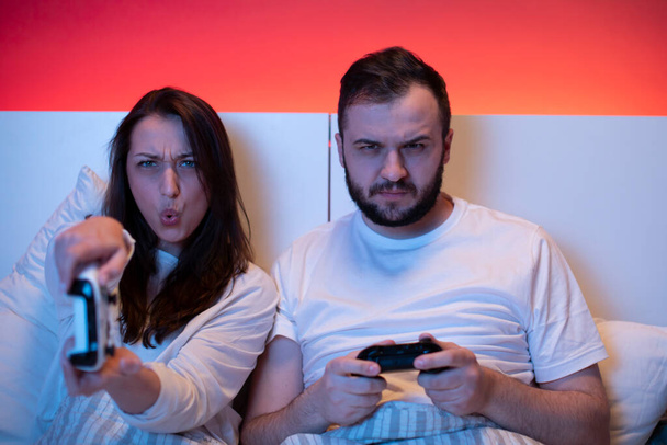 Liebespaar spielt leidenschaftlich und emotional Videospiele im Bett - Foto, Bild