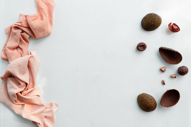 Roze gekleurde stof geverfd met avocado huiden en pitten. Bovenaanzicht met kopieerruimte. Witte achtergrond - Foto, afbeelding