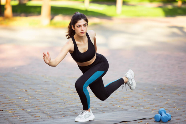 Young female athlete training in the city street in summer sunshine. Beautiful woman practicing, working out. Concept of sport, healthy lifestyle, movement, activity. - Foto, Imagen