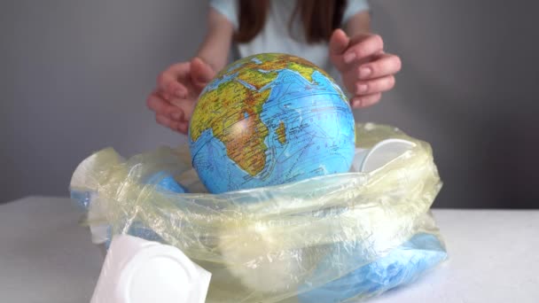 Woman is pulling out an Earth in form globe of a pile of plastic garbage. Environmental pollution and saving the planet - Materiał filmowy, wideo