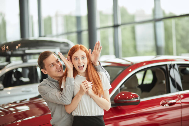 Man making surprise for his wife, buying her a new car at dealership. - Foto, Bild