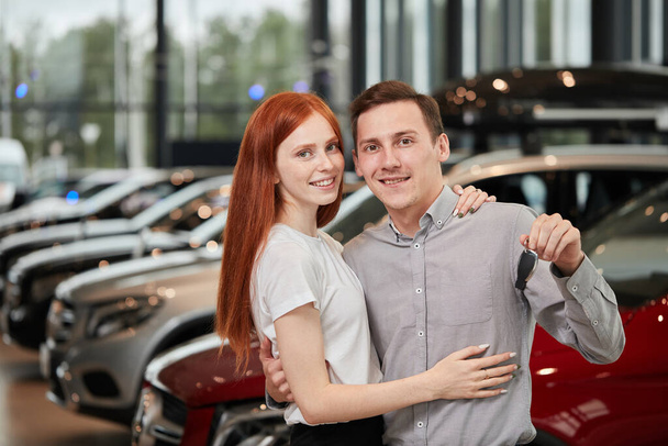 Beautiful couple is holding key of their new car, looking at camera and smiling - Photo, Image