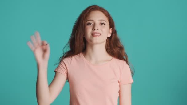 Beautiful cheerful redhead girl happily showing ok gesture on camera over colorful background - Séquence, vidéo