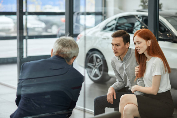 Happy beautiful couple is buying a new car at dealership. Family council - Foto, immagini
