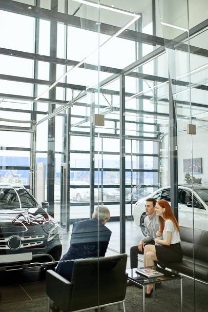 Happy beautiful couple is buying a new car at dealership. Family council - Foto, Imagen