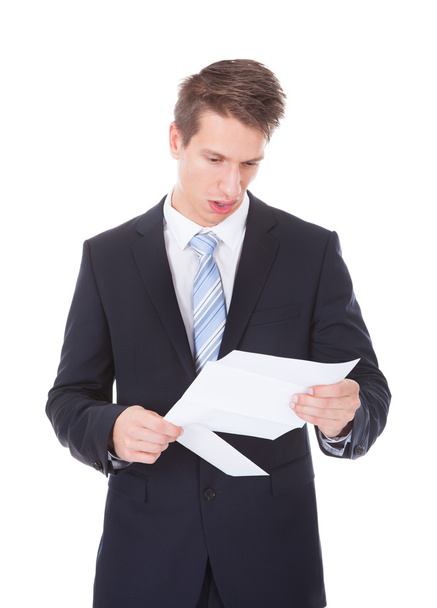 Young Businessman Reading Document Over White Background - Foto, Imagem