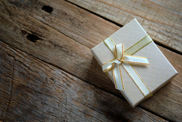 Schachtel mit Geschenkschleife mit rustikalem Holzhintergrund - Foto, Bild