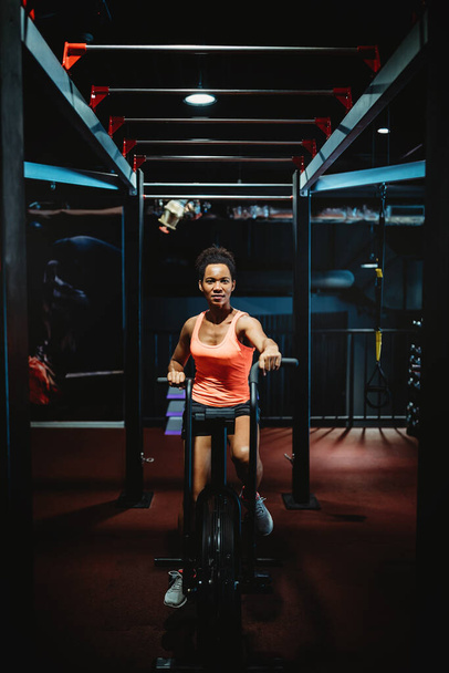 Fit african woman working out on the exercise bike at the gym - Photo, Image
