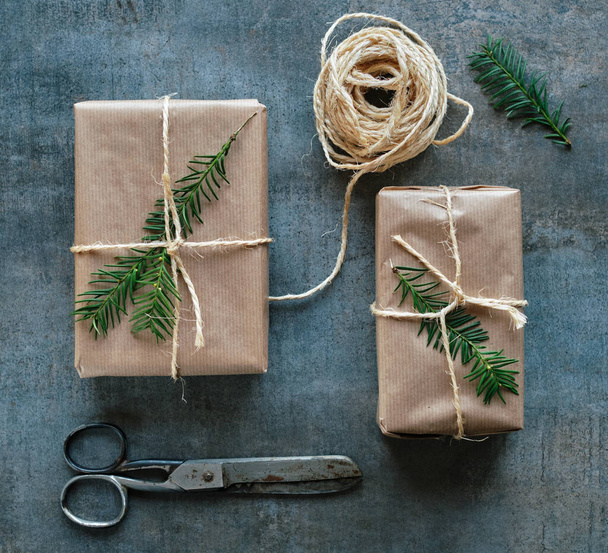 Gift packages wrapped with kraft paper and scissors on rustic ceramics - Photo, Image