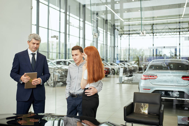 Happy beautiful couple is buying a new car at dealership. Family council - Foto, Bild