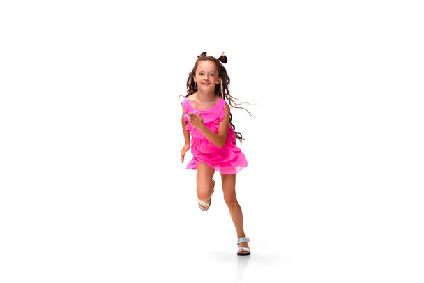 Happy little caucasian girl jumping and running isolated on white background - Фото, зображення