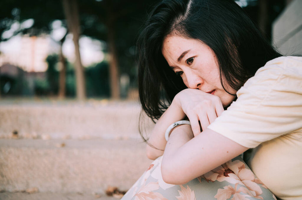 Mujer asiática sentada sola y deprimida, dejar de abusar de la violencia doméstica, ansiedad por la salud. - Foto, imagen
