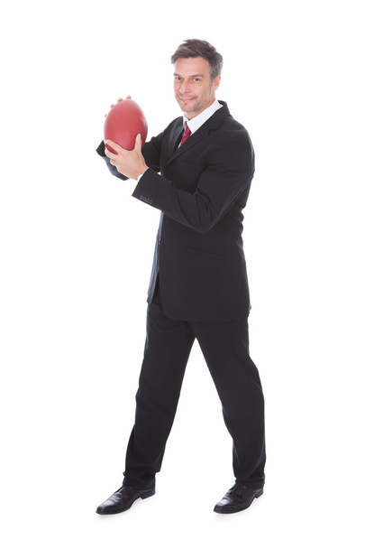 Бизнесмен, держащий регбийный мяч
 - Фото, изображение