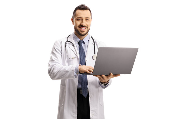 Male doctor holding a laptop and looking at the camera isolated on white background - Фото, изображение