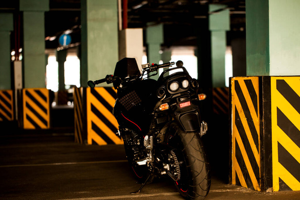 Moto nera sullo sfondo del parcheggio sotterraneo. - Foto, immagini