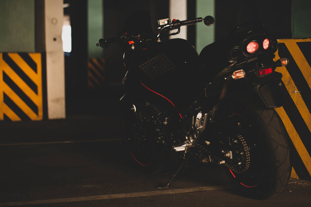 Zwarte motorfiets op de achtergrond van ondergrondse parking. - Foto, afbeelding