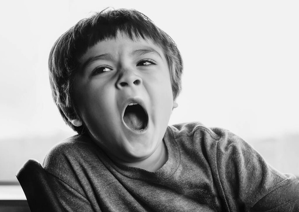 Close up face of Kid ziewanie kłamstwa, Senny dziecko ziewanie i patrząc w dół, Czarno-białe Indoor portret zmęczony dziecko się przeziębić podczas zmiany pogody, Koncepcja opieki zdrowotnej dzieci - Zdjęcie, obraz