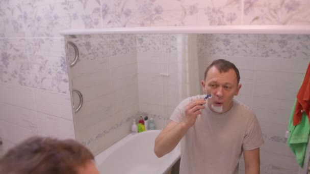 El hombre de la mañana de pie en el baño cerca del espejo se afeita, movimiento de la cámara
 - Imágenes, Vídeo