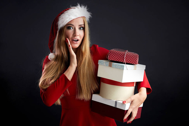 Young happy woman in Christmas Santa hat holds new year gift isolated over black - Foto, Imagen