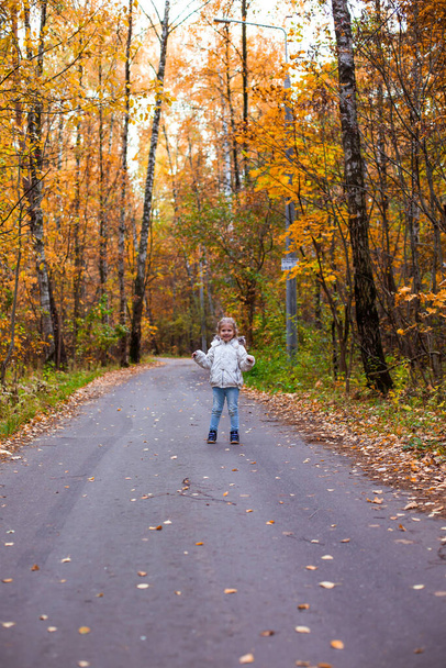 petite fille marchant dans la forêt d'automne en vêtements blancs dans la route - Photo, image