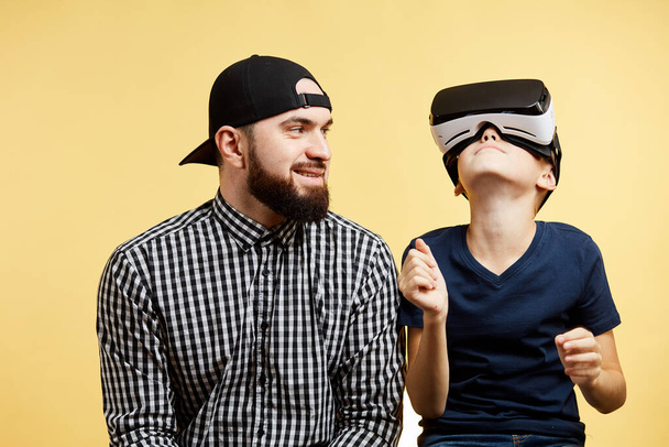 son uses virtual reality glasses near father. Future Technology Concept - Foto, Imagen