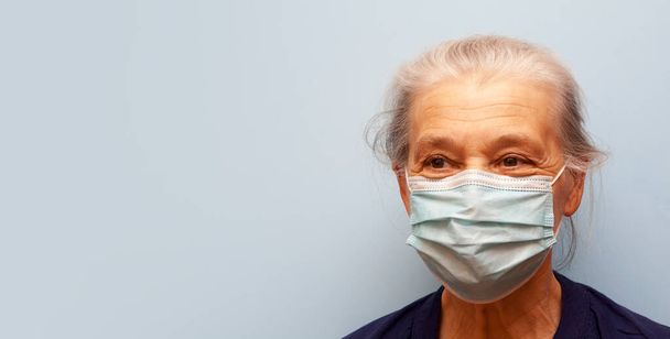 Старша жінка в медичній масці на синьому фоні з копіювальним простором
 - Фото, зображення