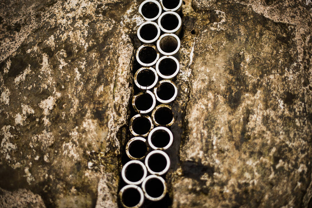 Un grupo de círculos / tubos metálicos juntos en medio de una textura rocosa - Foto, imagen