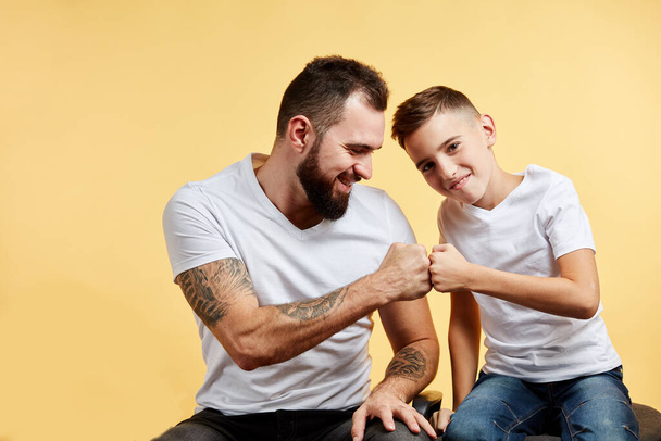 father and son with pleasant smile give fist bump to each other - Foto, Bild
