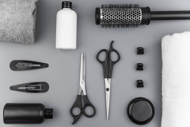 Professionelle Friseurwerkzeuge mit Kopierraum. Friseurausrüstung auf grauem Hintergrund. Schere, Bürste, Haarbürste, Balsam flach von oben. - Foto, Bild