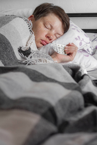 Felnőtt barna nő alszik az ágyban alatt kockás takaró, fogalma betegség vagy hideg, kezelés otthon, szelektív fókusz - Fotó, kép