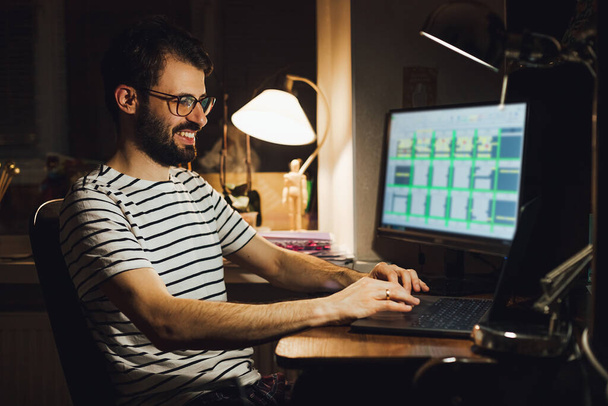 adult bearded man working sitting at home desk at computer, working online - Fotografie, Obrázek