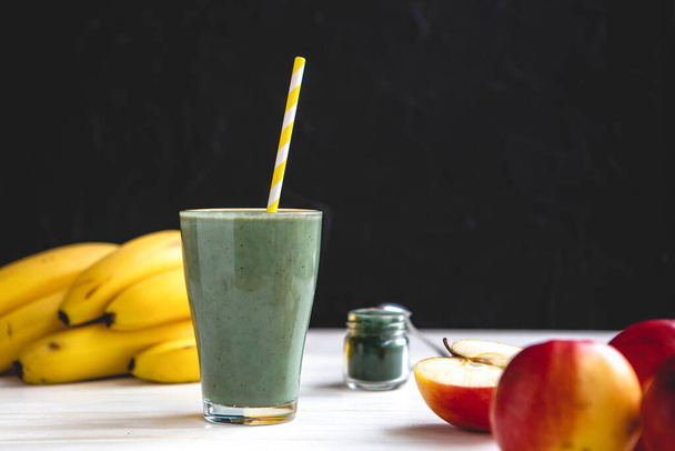 The concept of food and drink, diet and nutrition. Healthy green vegan smoothie with banana, spirulina and ripe apple for summer detoxification - Φωτογραφία, εικόνα