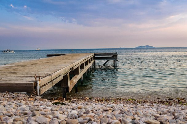 um velho cais de madeira se estende para o mar aberto
 - Foto, Imagem