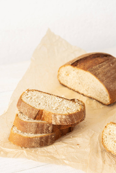 Αφρώδες σπιτικό ψωμί με φέτες ψωμιού από σιτάρι και σπόρους σε λαδόκολλα - Φωτογραφία, εικόνα