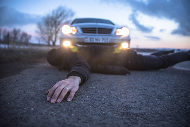 man lying in road with car - 写真・画像