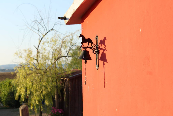Μεταλλική πινακίδα καλωσορίσματος στην πόρτα με γλυπτική αλόγου.-κόκκινο φόντο στον τοίχο - Φωτογραφία, εικόνα