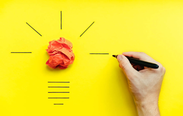 Light bulb over yellow background in vision and idea conceptual image. Symbol of business strategy. Conceptual image of brainstorming, innovation creativity. Marker in hand draws a straight line - Fotoğraf, Görsel