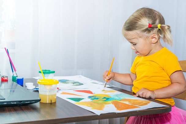 少女は注意深く絵を描く。子供は家での創造性に非常に興味があります. - 写真・画像