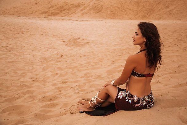 Beautiful girl dancing ethnic dances in desert. Beautiful belly dancer - 写真・画像