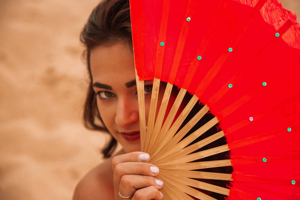Woman standing in desert with red fans. Portrait close up - Photo, Image