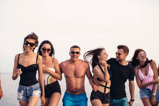 Group of Friends Walking at Beach, having fun, womans piggyback on mans, funny vacation - Photo, image
