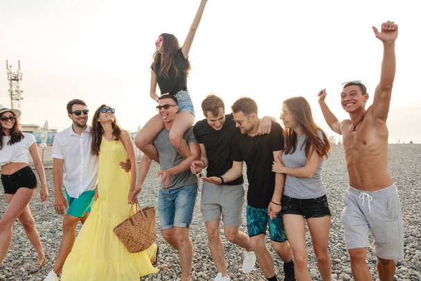 Group of Friends Walking at Beach, having fun, womans piggyback on mans, funny vacation - Foto, imagen