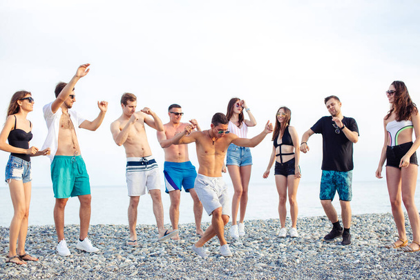 Friends dance on beach under sunset sunlight, having fun, happy, enjoy - Foto, imagen