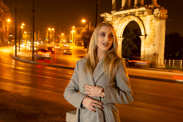 Beautiful Young Woman In A City At Night in front of handrian gate -  nightlife in a city project - Zdjęcie, obraz