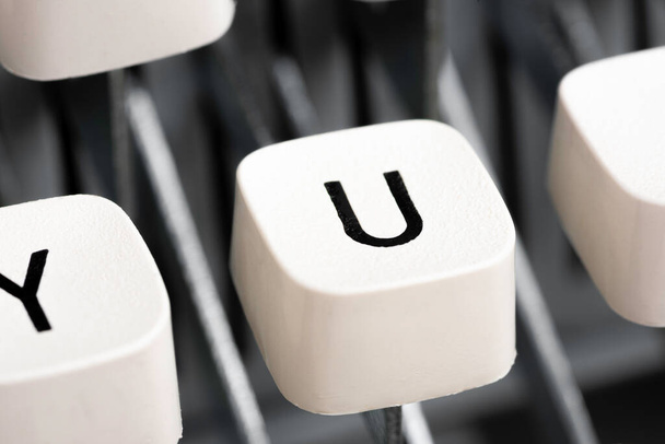 Um close-up extremo ou macro shot de uma tecla de teclado de plástico branco de uma máquina de escrever manual com profundidade de campo rasa e foco seletivo. - Foto, Imagem
