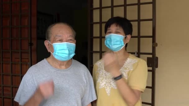 Elderly couple standing, wearing and adjusting medical face mask of each other. - Video, Çekim