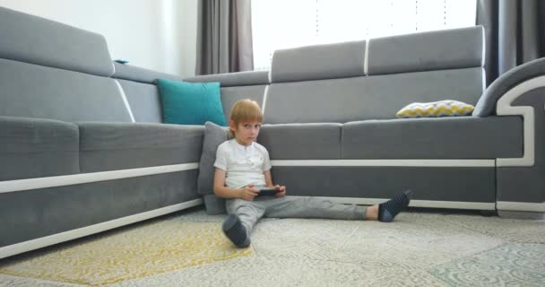 Little Boy Uses Phone To Play Or Learn Staying At Home, Caucasian Boy In Casual Wear Spends Time Playing Or Learning On Phone At Home, Little Boy Needs To Stay At Home Due To Quarantine - Video, Çekim