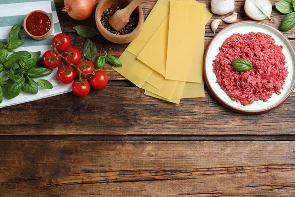 Fresh lasagna ingredients on wooden table, flat lay. Space for text - 写真・画像