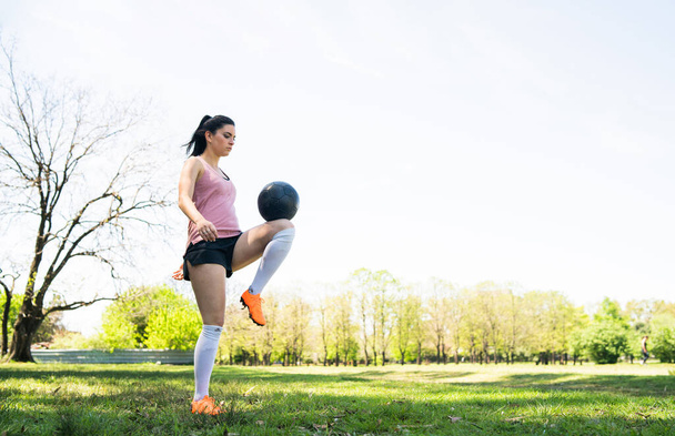 Portrait of young female soccer player training and practicing skills on football field. Sports concept. - 写真・画像